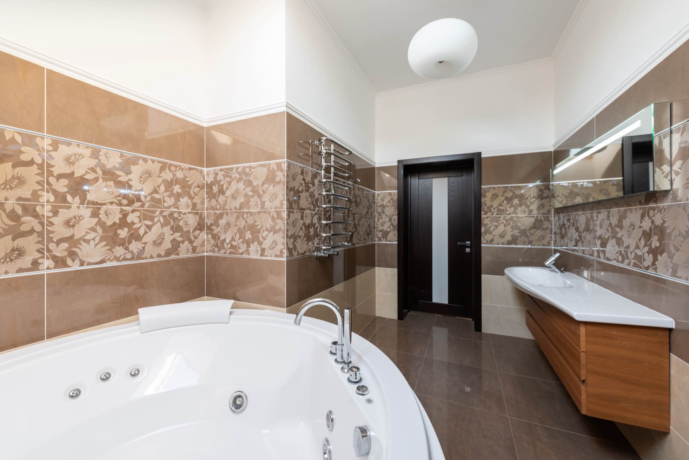 A bright bathroom with a corner soaking tub and a floating wood vanity
