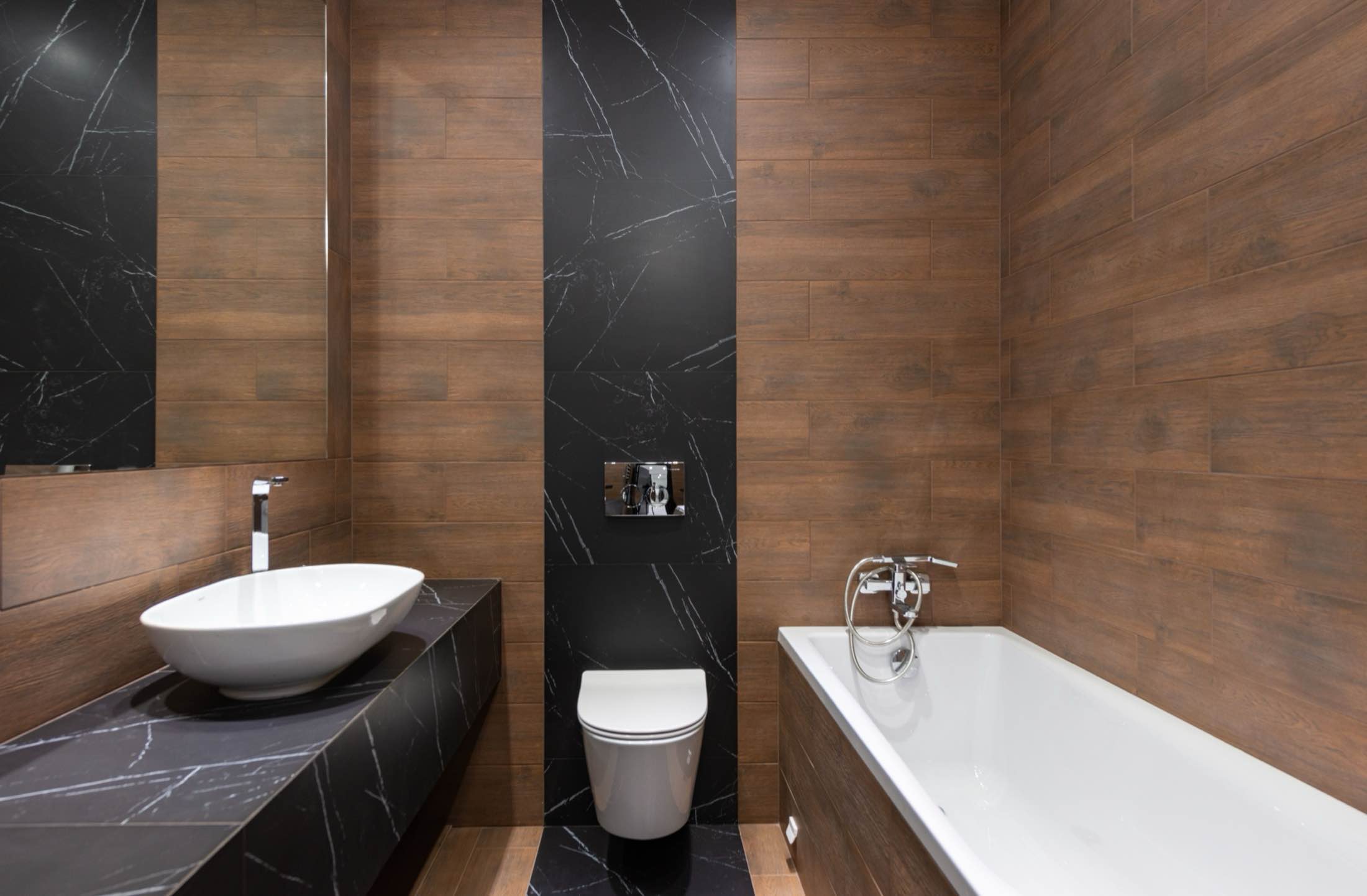 A bathroom pairing wood paneling with black marble, a vessel basin and a built-in tub