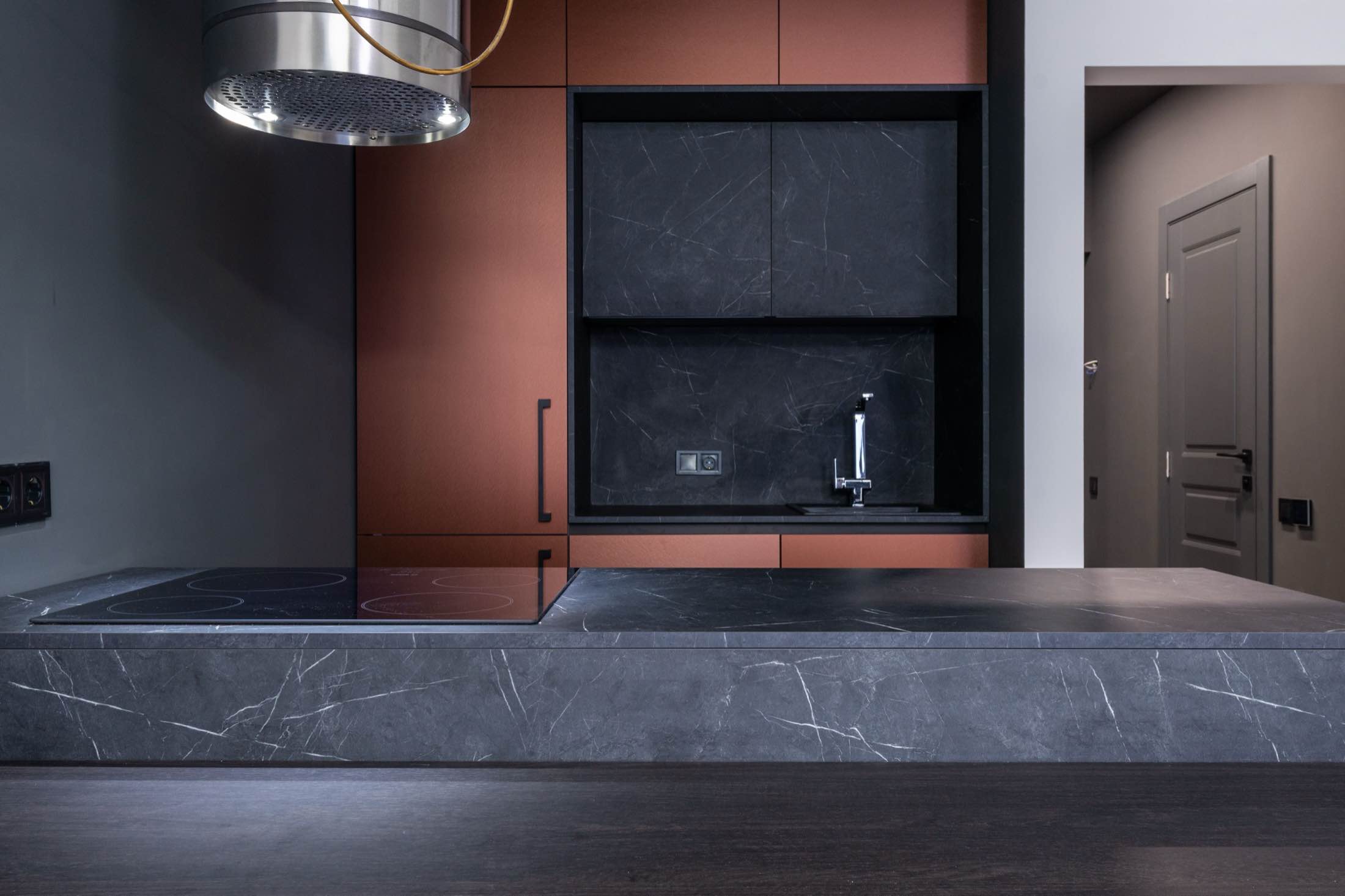 A kitchen with a long dark stone counter and an integrated sink