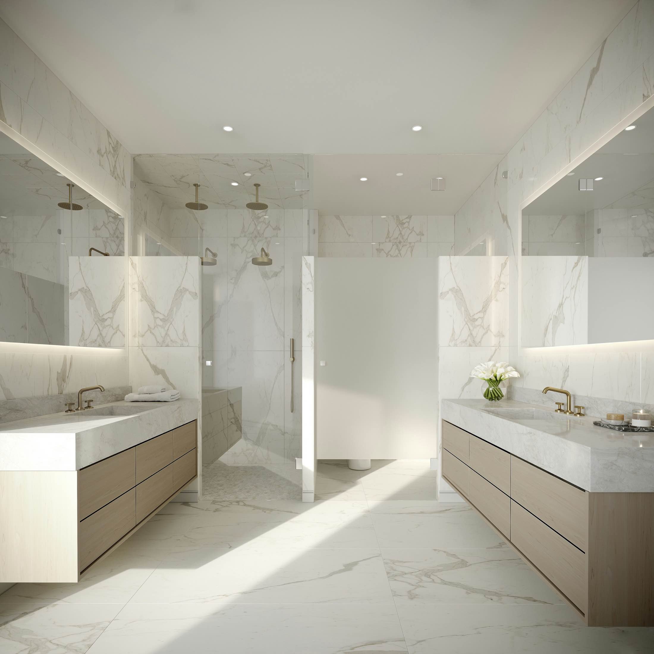 A white marble bathroom with a long vanity and a glass shower